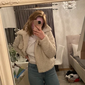 Fluffig jacka  - Säljer en fluffig fin jacka som är lite svår att sätta färgen på, därför jag har en vit hoodie så ni ser att den inte är vit.   Köpt på nakd tror jag för cirka 5 månader sen och värmer väldigt bra. Dock kom den inte till användning då det blev sommar och nu inte är min stil, så i stort sätt oanvänd.   Storlek M 