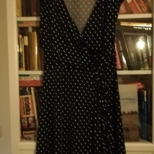 Prickig klänning - Marinblå klänning med vita prickar i strl 40/42 M, men jag tycker att den är en mkt stor M mot L. 95% polyester och 5 % elestan. Använd mycket lite. Sval och skön till sommaren med smickrande omlott. 