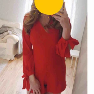  - Röd/coral färgad jumpsuit från Chiquelle. Använd 1 gång. Storlek 38 (S/M). Öppningar i armarna, en mindre öppning i ryggen och rosett 