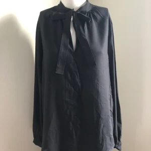 Svart knytblus  - Svart knytblus från Sara Kelly i storlek 34 men skulle säga att den passar 34-38. Oanvänd.