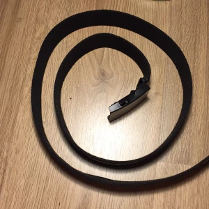 Skärp - Ett svart skärp med en gul rand i mitten. Aldrig använd och väldig bra skick. 