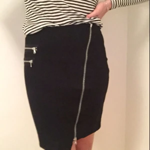  - Kjol med sned dragkedja rakt över samt 2 dekorativa dragkedjor på sidan. 