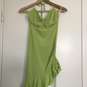  - Söt 90-tals klänning i limegrön färg. Halterneck och knytband i sidan så att man kan justera draperingen och fallet på klänningen. Stretch-material i storlek XS/S. Köparen står för frakten, betalning via swish eller bankkonto. Upphämtning i Linköping går bra. Kolla gärna in mina andra annonser - garderobsrensning! 