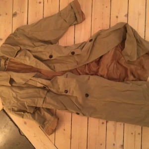  - Jättefin trenchcoat tillverkad i bomull och syntetblandning, passar storlek 40.  Sparsamt använd och fin kvalitet, sitter supersnyggt på. Köpt i en vintagebutik i Amsterdam. Riktigt kap.