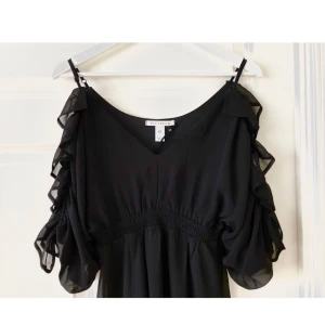  - Svart klänning från NLY TREND med frill och öppna ärmar. Oanvänd, prislapp kvar! 