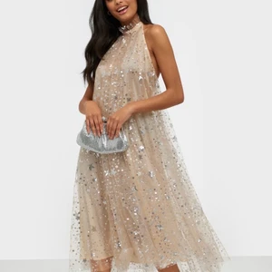 Ida Sjöstedt happy dress  - Klänning från Ida Sjöstedt i halterneck modell. Öppen rygg med rundad ringning. Tyll med dekorativa sömmar och paljetter.