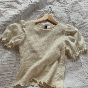 Smockad topp med puffärm - Säljer denna drömmigt toppen som jag hade på min student då den inte är min stil riktigt :/ jättefin dock, önskar jag passade i den! Storlek S men väldigt strechig i o med det smockade tyget. Fri frakt