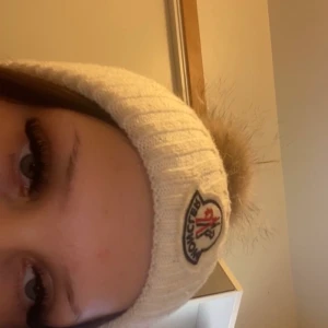 Moncler mössa - Moncler mössa,  vet inte om den är äkta. Stor äkta pälsboll. Buda gärna. Kan sänka priset vid snabb affär.