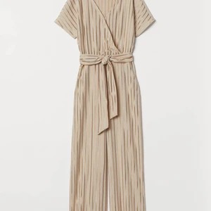 Creppad beige jumpsuit - H&M: ”En ankellång jumpsuit i skir, crêppad trikå med avtagbart knytband i midjan. Jumpsuiten är v-ringad med omlottlagd överdel och dold hyska och hake. Kort pingvinärm och avskärning med resår i midjan. Vida, lätt avsmalnande ben.” Använd 1-2 ggr.