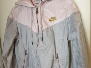 Nike jacka i nyskick - Nike jacka i ljusrosa/grått, som endast är använd ett fåtal ggr. Inte en enda 'noppra' på innertyget, som är i sweatshirt material. Liten i strl. 