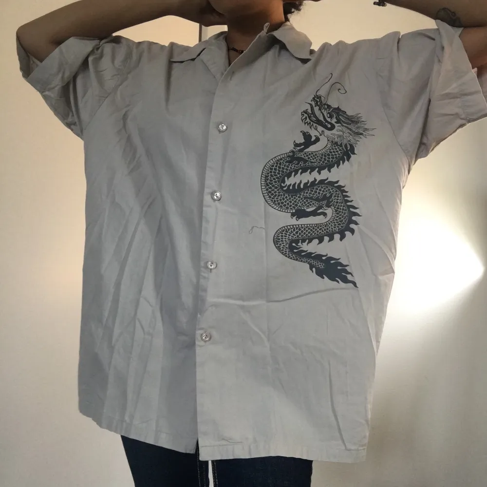 Super cool kortärmad grå skjorta med en drake på! Skön och bra kvalité. Använt endast mågra få gånger. Skickar fler bilder om det önskas 😊 (frakt:44kr)🌸. Skjortor.