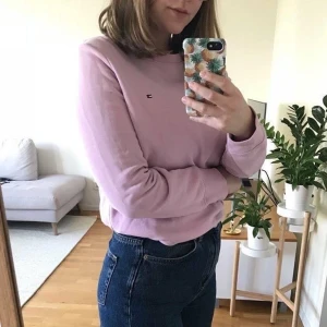Tommy Hilfiger tröja - Ljust lila/rosa tjocktröja från Tommy Hilfiger. Har några små fläckar (se bild). Möts gärna upp i Stockholm men annars betalar köpare frakt.