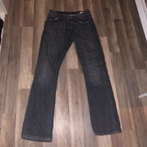 Grå Nudie Jeans - assnygga gråa lågmidjade bootcut jeans från nudie i w32/L34. man ser färgen bättre på sista bilden. köpta second hand, riktigt bra skick utöver hålet/repan nere på benet (syns på andra bilden). innerbenslängd 86 cm. möts elr köparen står för frakt