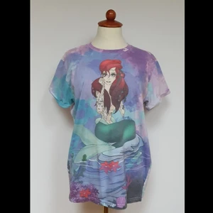 Ariel T-shirt - T-shirt med tatuerad Ariel. Jätte skön och lite annorlunda tröja som är använd några gånger men fortfarande i original kvalitet. Den har en ganska rak form💜💙💚
