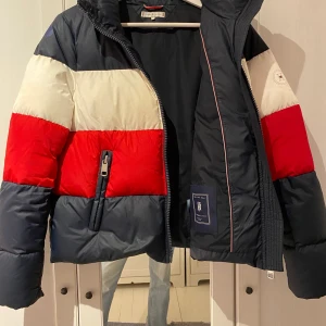 Hilfiger vinterjacka - Hilfiger vinterjacka köpt för 2 år sedan, används då och då, men ingenting alls det senaste året och därför säljer jag. Sitter skönt, rymlig och är varm. En lagning på höger axel, därför sänkt pris, köptes för 2200kr. Skriv för fler bilder:) 
