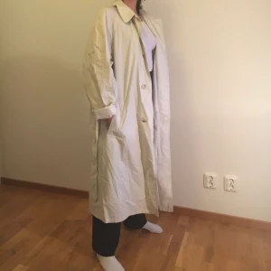 Trenchcoat - Lång lite oversized jacka. Har två fickor där fram. Är beige. Passar S och M, även XS men då kan den va ganska oversized.