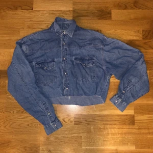 Cropped denim skjorta - Lite skrynlig då jag ej strykt eftersom som jag inte har använt den på länge. Fin ljus blå denim färg med mozaik knappar. Skönt material. Inte så tajt. Passar M, L och tom S (oversized) :3 