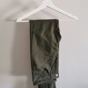 Khaki ankelbyxor från Bikbok - Snygga ankelbyxor från Bikbok, guldiga detaljer. I princip oanvända, riktigt fint skick! Köparen står för frakt. 