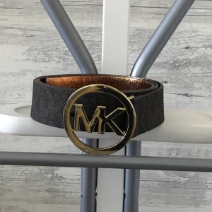 Äkta Michael Kors Skärp  - Ett äkta (självklart) michael kors skärp som inte är använt en enda gång. Köptes i USA , är ganska stort , man får bara göra några extra hål i det så passar det perfekt!! väldigt fint, men inte något som kommer till användning🤍 små slitningar av flygresan