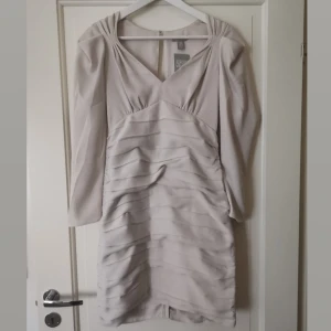 Beige klänning med fina detaljer - Köpte denna i två storlekar och glömde att returnera så säljer den i strl 38. Ligger i oöppnad förpackning. Riktigt fin klänning. Köparen står för frakten 