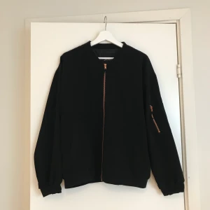 Svart bomberjacka från Monki i storlek XS/S - Så fin oversized bomberjacka från Monki i storlek XS/S. Dragkedjorna är i roseguld! Använd vid ett fåtal tillfällen så jättefint skick!
