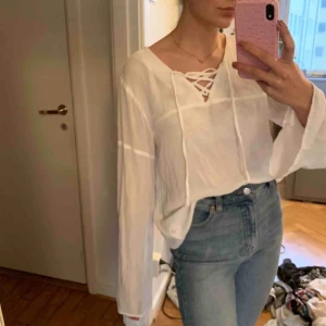  - Vit blus i linneliknande material med vida ärmar och snörning vid halsen. Priset är exklusive frakt. 