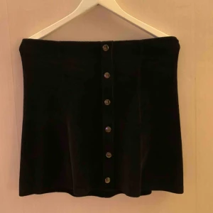  - Svart ribbad kjol med fusk knappar från gina tricot. Manchester imitation. Kjolen innehåller 3% elastan.   Kan mötas upp i Borås, eventuellt Göteborg, annars står köparen för frakten. 