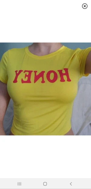 Gul topp - Gul lite cropped T-shirt från FANCYQUBE. Text: HONEY💛Härligt lent o stretchigt material-perfa till sommaren, elr våren med ett par högmidjade jeans. Gott skick då endast testad. Säljes pga kommer ej till användning för min del. 