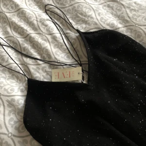  - ”NLY Eve All Over Sparkle Gown”  Helt ny oanvänd långklänning till fest. Inköpt på Nelly.  Det är en slimmad modell, lång och slits i sidan.  Material: yttertyg 100% polyester. Foder: 100% polyester.  Köpare står för frakt alt. Hämtar i täby, Stockholm.  