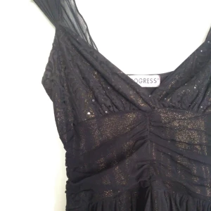  - Härlig festklänning med guldglitter i undertyget och paljetter. Den har massvis med härliga detaljer, och träs enkelt på utan knappar eller dragkedjor. Toppenklänning, men jag har tyvärr vuxit ur den. Köpt utomlands. Gratis frakt!  