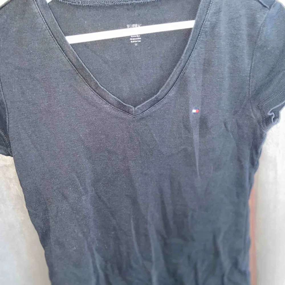 Svart t-skirt från Tommy Hilfiger, använd många gånger men i ett forfarande fint skick, denna tröja går att matcha till det mesta.. T-shirts.