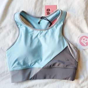 Cropped top från Ashy Bines - Aldrig använd sporttopp från Toned by Ashy Bines. Blå/grå i skönt material!