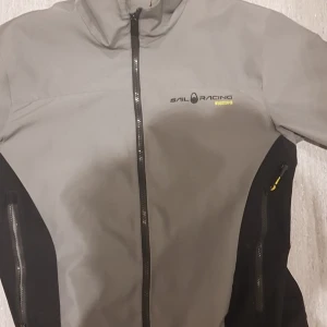 Sail racing jacka -  Grå Sail racing vindjacka mdd gula detaljer. Sparsamt använd och ser helt ny ut. Jackan passar även tjejer med storlek M.