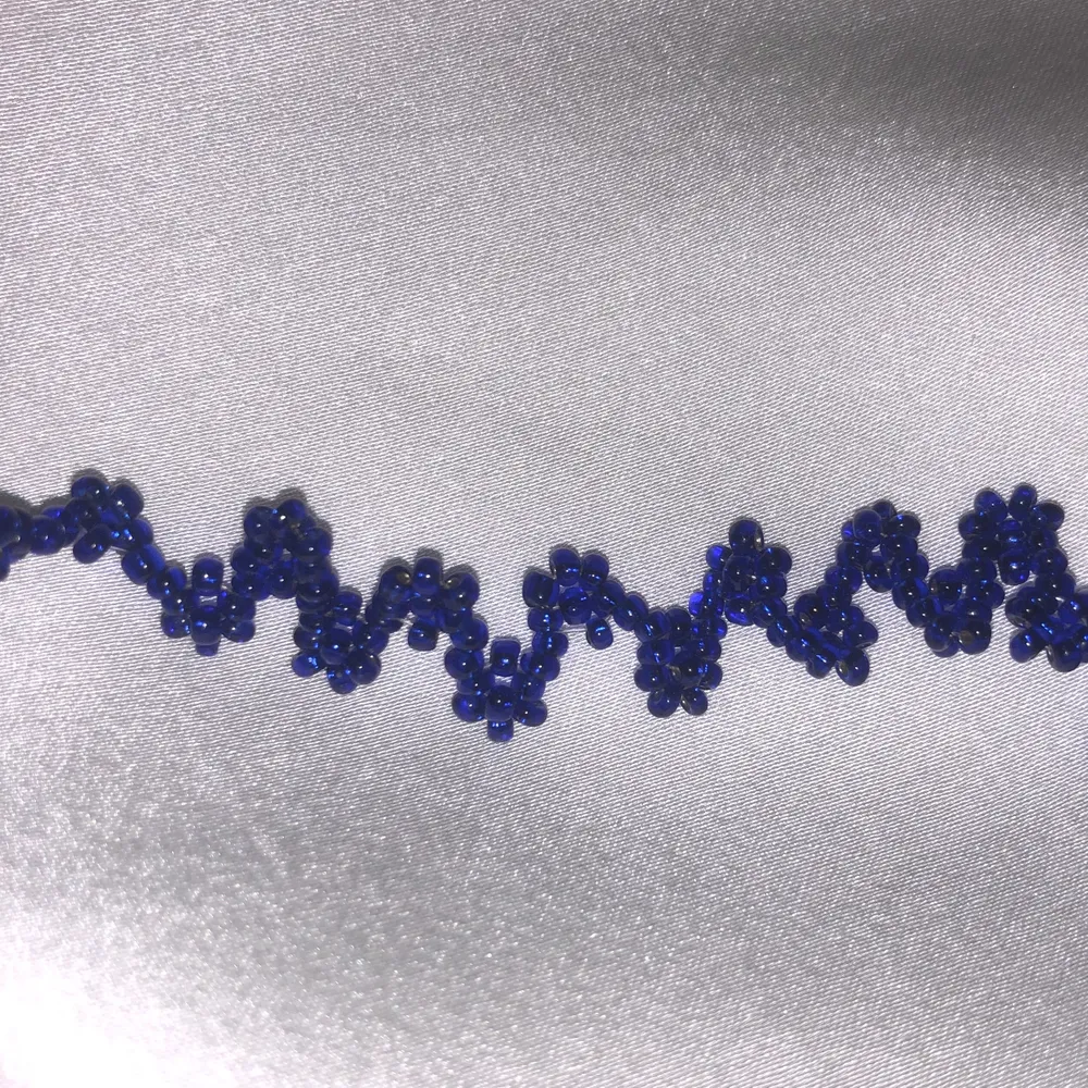 Supercoolt halsband i chokermodell med zigzag och blommönster i fina blåa beads! One-of-a-kind och piffar upp alla outfits🥰. Accessoarer.