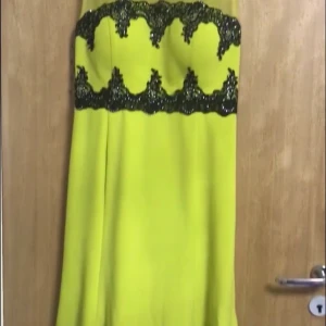En gul klänning  - Klänningen är gul och svart med silverdetalier.Klänninegn är använd 1 gång och har storleken 46