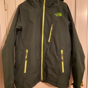 The North Face jacka  - Skidjacka från The north face med snölås. Strlk M på lappen men känns mer som L / XL. Mörkgrön med ”neon”detaljer. 