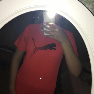 Puma t-shirt och mjukisbyxer - Det är en puma t-shirt, helorange med ett svart puma märke på bröstet. Materialet är tunt. Använd ett antal gånger bara.( den har en underdel också)skulle ta 75kr för både över och underdel.