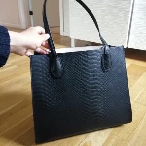 Ormskinn väska  - I mycket bra skick då den använts sällan. Dock lite smutsig inuti, se bild 3. Man kan justera så att väskan blir större sidledes. 