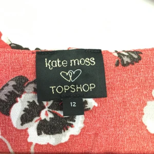 Kate Moss omlottklänning - Sommarklänning från topshop i kollektion från Kate Moss. Kort klänning rosa/röd med blommor på. Passar S, omlott med snörning