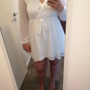 Nelly klänning strl M - Fin, vit klänning i omlotteffekt i fint skick. Använd högst 2-3 gånger. 