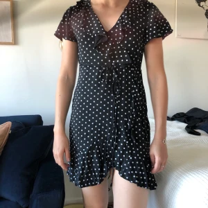 Klänning från boohoo - Svart klänning med vita prickar och volangdetaljer från Boohoo. Storlek 10 (ca 38). Helt nyinköpt, aldrig använd. Kan hämtas i Malmö/Lund annars tillkommer frakt. 