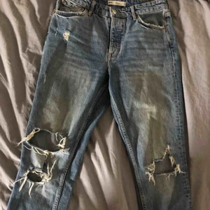  - Mom jeans ifrån Gina Tricot i modellen Serena med slitningar på knäna/låren. Målat på båda fickorna och broderat en sida av en kropp på ena vaden. 