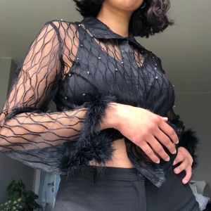 Strl S-M - Ett secondhand KAP!!! Genomskinlig skjorta i fint mönster med strass och fluff;-) den är i fint skick utöver att någon strass trillat av samt fluffen är lite snurrad på ett ställe (tror det går att rätta till!) (frakt ingår ej i priset) 