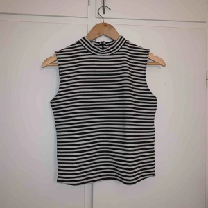  - En jättefin tajt randig topp med en liten högre krage utan ärmar! Använd endast en gång! 