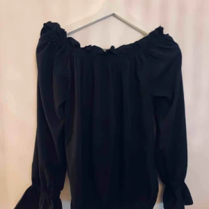  - Svart offshoulder top från Nelly Trend. Men resår upptill, nertill och trumpetärmar. Använd ett fåtal gånger .