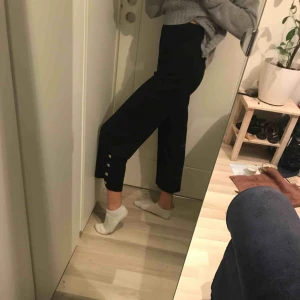  - Svarta kostymbyxor med guldiga knappar på sidorna. Bra skick förutom att knapparna är lite slitna. OBS. Jag har långa ben och brukar ha byxor med 34” i längd för att jämföra. Möts i slussen eller så tillkommer frakt.