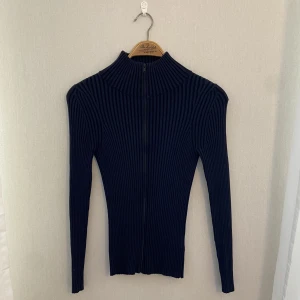 Kofta från COS - Mörkblå ribbstickad kofta från COS. Första bilden visar färgen bäst. I mycket bra skick. Kragen går att ha uppvikt och nervikt. 