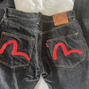 Evisu jeans  - Supercoola evisujeans med röda detaljer i nyskick. Storlek 32. Pris går att diskutera!🌹