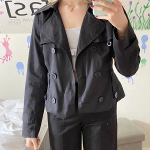 Kort trenchcoat från vero moda - Kort trenchcoat från vero moda. Jag har vikt upp den så den är egentligen något längre, medföljer även ett skärp. Köpt på plick och i bra skick!