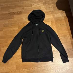 En svart lyle and scott zip hoodie som är i storlek M. Den är knappt använd. Nypris ca. 900kr